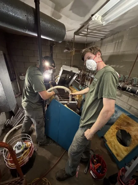Two SOS technicians servicing a boiler in a Rhode Island basement