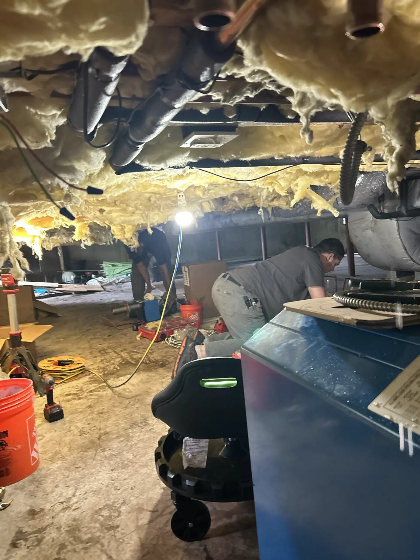 SOS technicians working in a tight Rhode Island crawlspace during an emergency service call