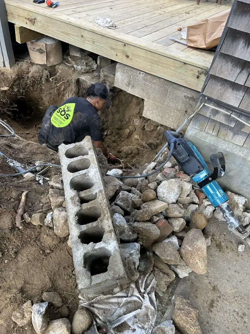 SOS technician excavating to reach a buried sewer line on a Rhode Island property
