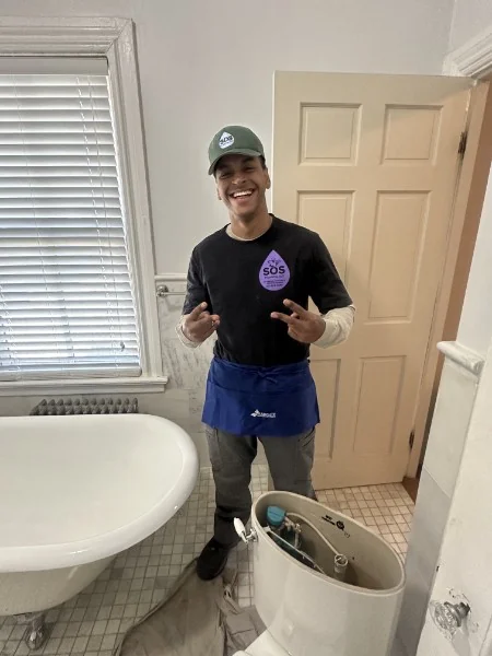 SOS plumber in a branded shirt after completing a toilet installation in a Rhode Island bathroom