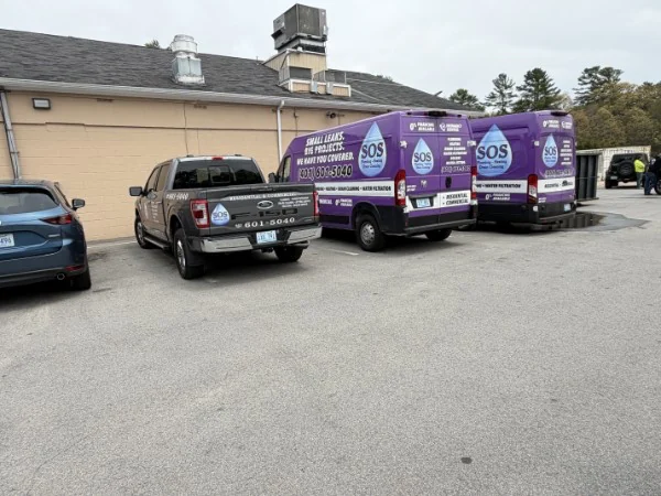 Two branded SOS Plumbing & Heating vans and a service truck at the West Warwick shop