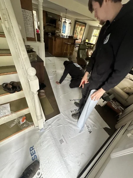 SOS plumbers laying protective floor covering inside a Rhode Island home before starting work