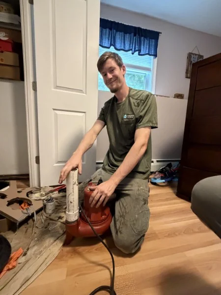 SOS technician installing a new sump pump and discharge line in a Rhode Island home