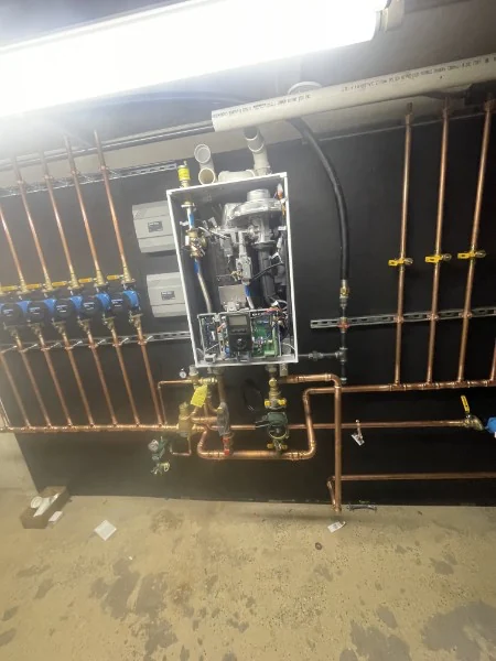 Wall-hung Navien tankless unit with copper manifold and zone pumps installed by SOS in Rhode Island